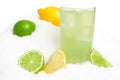 Glass of lime juice with ice cubes,limes and lemons halves on snow on white Royalty Free Stock Photo