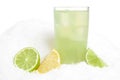 Glass of lime juice with ice cubes,limes and lemons halves on snow on white Royalty Free Stock Photo