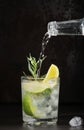 Glass of lime lemonade on dark table, summer drinks. Pure mineral water is poured into glass. Vertical frame, selective focus. Royalty Free Stock Photo