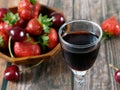 glass with liquor on juicy fresh tasty strawberries and cherry Royalty Free Stock Photo