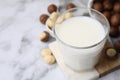 Glass of macadamia milk and nuts on white marble table, closeup. Space for text Royalty Free Stock Photo