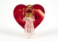 Glass made angel reading. Heart shape red greeting card with love sign made by hands behind it