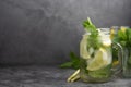 Glass mason jar of ice tea with fresh mint, lemon and paper straw on dark background. Summer healthy cold drink. Copy space