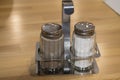 Glass and metal set salt and pepper shaker on a wooden table in a cafe, close-up Royalty Free Stock Photo