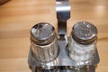 Glass and metal set salt and pepper shaker on a wooden table in a cafe, close-up Royalty Free Stock Photo