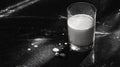 Glass of milk on black marble surface with spilled drops and light play Royalty Free Stock Photo