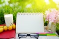 Glass of milk, blank page calendar, yellow fruit,sunglasses, pencils and pink flower on white wood table over green grass Royalty Free Stock Photo