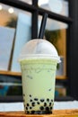 Glass of milk bubble matcha green tea with tapioca pearls on blurred cafe restaurant background Royalty Free Stock Photo