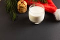 Glass of milk, christmas cookies and santa hat with copy space on black background Royalty Free Stock Photo
