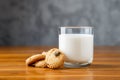 Glass of milk and cookies on wooden table.