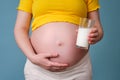 A glass of milk in the hands of a pregnant woman on a blue background