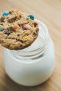 Glass of milk and homemade sugar cookies with colorful chocolate candies on a wooden board. Royalty Free Stock Photo