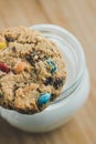 Glass of milk and homemade sugar cookies with colorful chocolate candies on a wooden board. Royalty Free Stock Photo