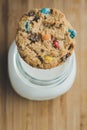 Glass of milk and homemade sugar cookies with colorful chocolate candies on a wooden board. Royalty Free Stock Photo