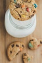 Glass of milk and homemade sugar cookies with colorful chocolate candies on a wooden board. Royalty Free Stock Photo