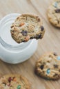 Glass of milk and homemade sugar cookies with colorful chocolate candies on a wooden board. Royalty Free Stock Photo