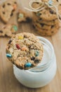 Glass of milk and homemade sugar cookies with colorful chocolate candies on a wooden board. Royalty Free Stock Photo