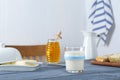 Glass with milk, honey, bread and butter on grey wooden table Royalty Free Stock Photo