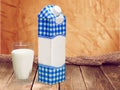 Glass of milk and package on wooden background