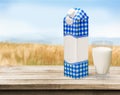 Glass of milk and package on wooden background