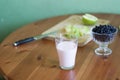 A glass of milk, a plate of apples, a bowl of blueberries on a green background