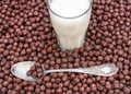 Glass of milk with spoon on the heap of chocolate corn balls