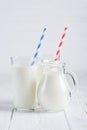 Glass of milk with stripped blue and red paper straws and jug of milk Royalty Free Stock Photo