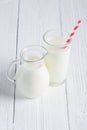 Glass of milk with stripped red paper straw and jug of milk Royalty Free Stock Photo