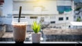 The glass of milk tea placed on a wooden table with flowers blurred Royalty Free Stock Photo