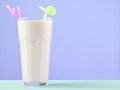 A glass of milkshake with a straw on a pastel color wooden table. Royalty Free Stock Photo