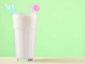 A glass of milkshake with a straw on a pastel color wooden table. Royalty Free Stock Photo