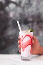 Glass of milkshake in woman hands on gray texture