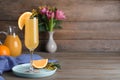 Glass of Mimosa cocktail with garnish on wooden table. Space for text