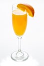 Glass of mimosa cocktail ready to be served for brunch with an orange slice on a white table