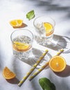 A glass of mineral water and a slice of orange on a gray table with fresh juicy fruit oranges with hard shadows. Summer time. Top Royalty Free Stock Photo