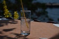 A glass with mineral water and a straw ,on a table.