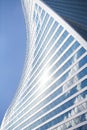 Glass mirror skyscraper wall spiral shape on blue sky, white clouds background, modern business center building