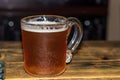 Glass misted mug with light beer and white foam on a brown wood background. Royalty Free Stock Photo