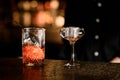 Glass for mixing a drink and a stemmed glass with ice are on the bar counter