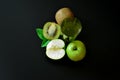 A glass of a mixture of fruit juices on a black background, next to pieces of a ripe kiwi fruit and half a green apple Royalty Free Stock Photo