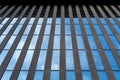 Glass modern skyscraper with blue sky background. Low angle view and architecture details. Windows of glass office building.