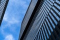 Glass modern skyscraper with blue sky background. Low angle view and architecture details. Windows of glass office building.