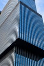 Glass modern skyscraper with blue sky background. Low angle view and architecture details. Windows of glass office building.