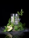 Glass of Mojito cocktail with ice cubes mint and lime on black background with fresh lime. Royalty Free Stock Photo