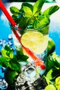 Glass of mojito with lime and mint ice cube close-up red straw on blue background Royalty Free Stock Photo