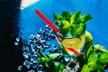 Glass of mojito with lime and mint ice cube close-up red straw on blue background Royalty Free Stock Photo