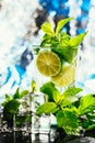 Glass of mojito with lime and mint ice cube close-up red straw on blue background Royalty Free Stock Photo