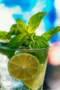 Glass of mojito with lime and mint ice cube close-up red straw on blue background Royalty Free Stock Photo