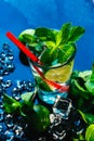 Glass of mojito with lime and mint ice cube close-up red straw on blue background Royalty Free Stock Photo