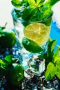 Glass of mojito with lime and mint ice cube close-up red straw on blue background Royalty Free Stock Photo